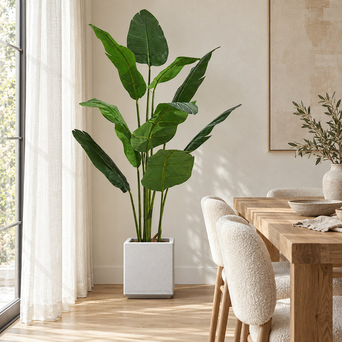 Artificial bird of paradise in a white planter by a dining table