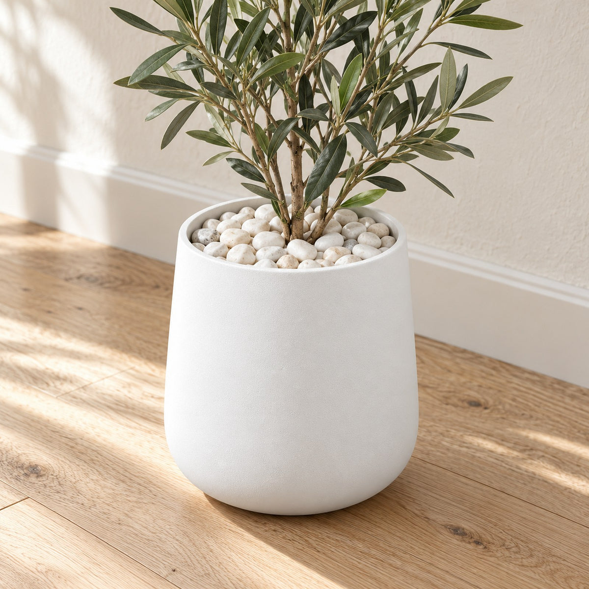 White Pebbles covering the top of a white planter with a plant